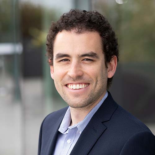 Man in a dark suit sits for a professional headshot.