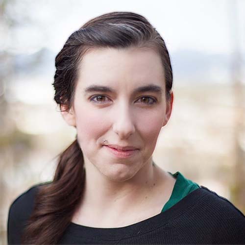 Woman with hair pulled back in a braid smiles for the camera with closed lips
