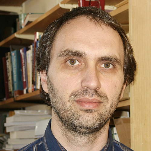 Professor standing in front of a book shelf for a photo