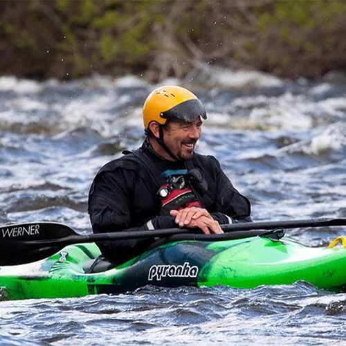 Man with a green helmet in a river kayaking