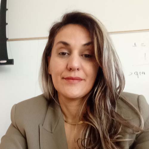 Woman with long dark hair sits in front of a whiteboard