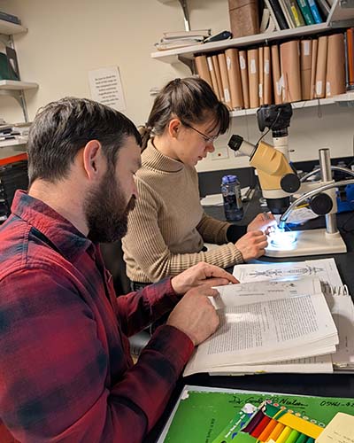 Faculty and a student work at a microscope in the LCRI Lab.